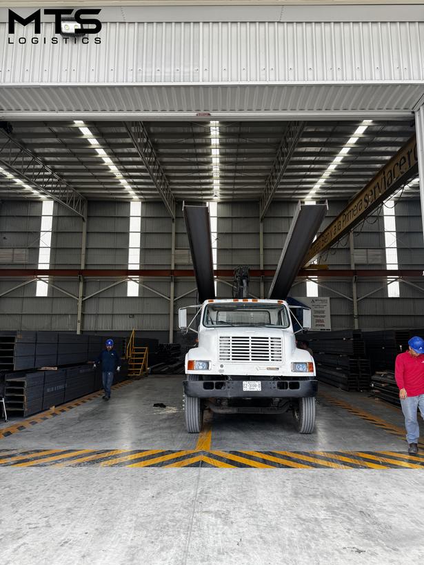 Camión de MTS Logistics transportando vigas de acero en nave industrial